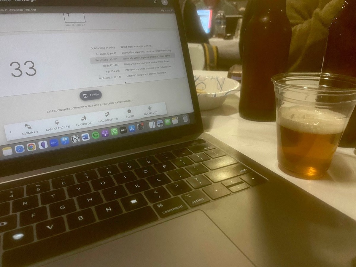 A laptop showing a BJCP beer scoresheet next to a cup of American pale ale at the National Homebrew Competition, judged at AleSmith Brewing Company in San Diego